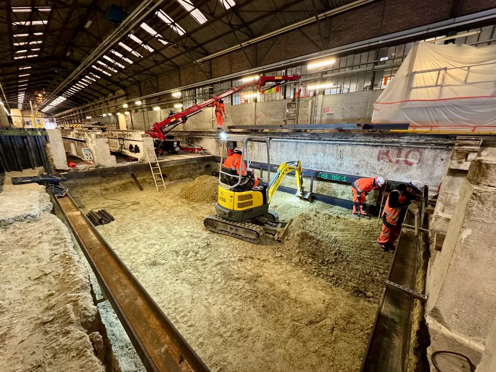 Fouille blindée sous la halle d’une gare, mini-pelle et compagnons au fond