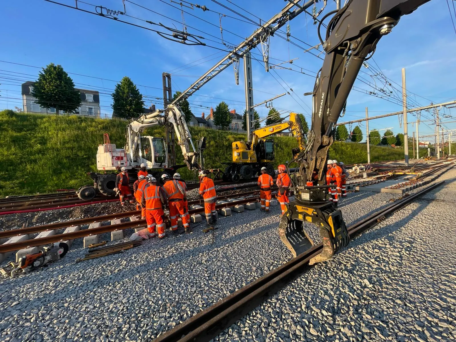 Chantier de renouvellement de voie : pelles rail-route et équipe en voie.